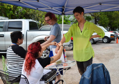 Volunteers putting wristbands on Gender Unbound attendees at event entrance.