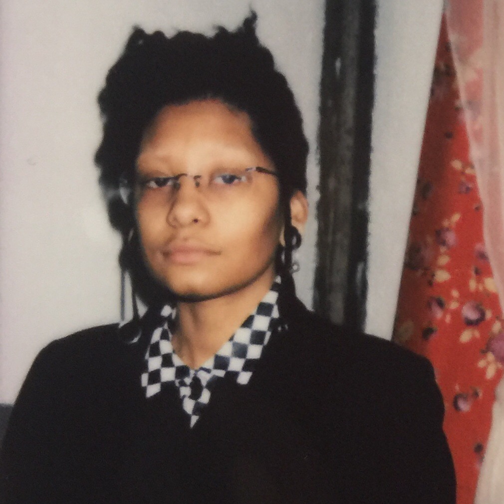 A photo of Shanisia standing and looking towards the viewer.